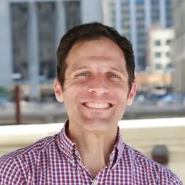 Jonathan R. Davis smiling outdoors in a red checked shirt